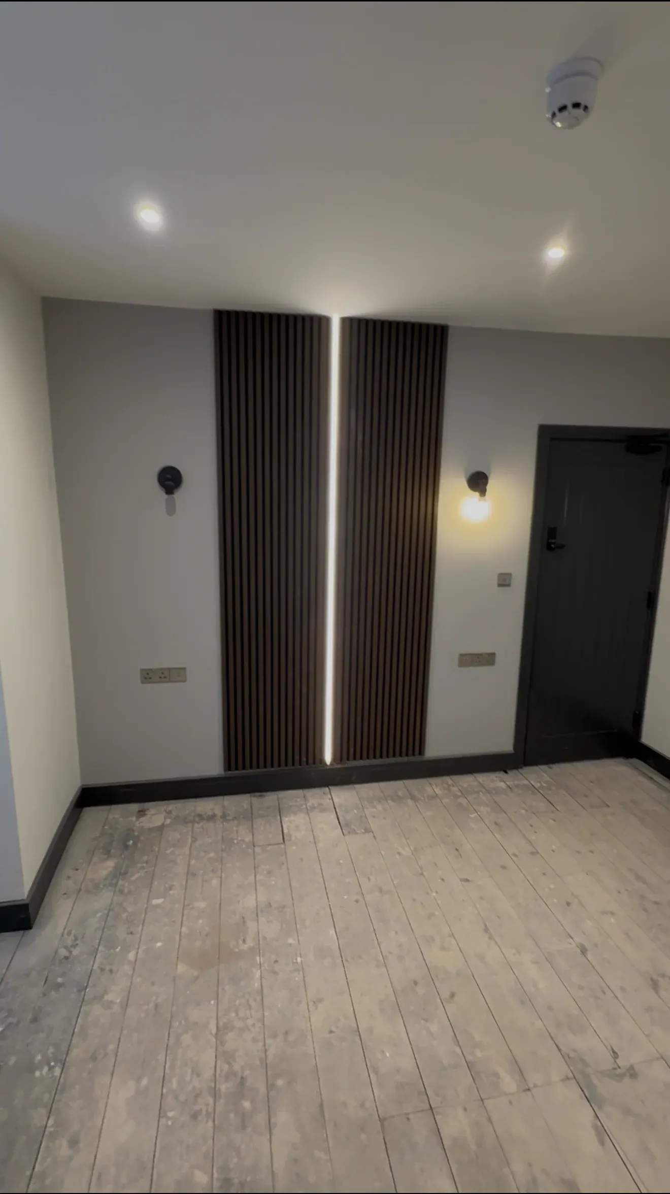 Detail of the slatted timber feature wall with concealed strip lighting and a wall light