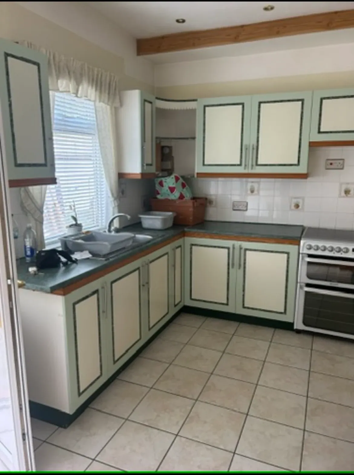 The original kitchen before work started — mint green units, patterned tiling and a tiled floor