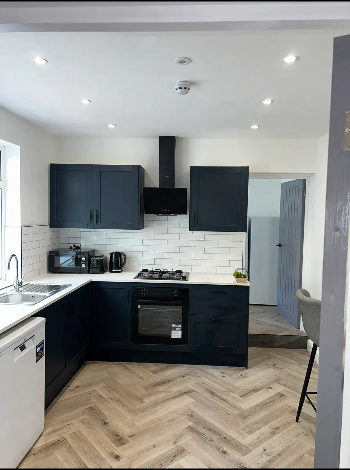 The finished communal kitchen at Etruria Road, with navy units, white worktops and herringbone flooring