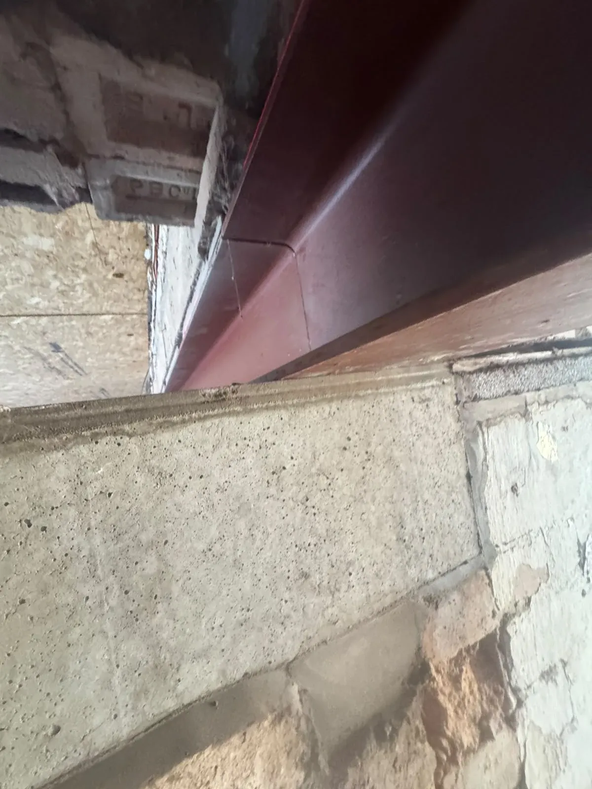 A painted steel beam spanning an opening between two rooms