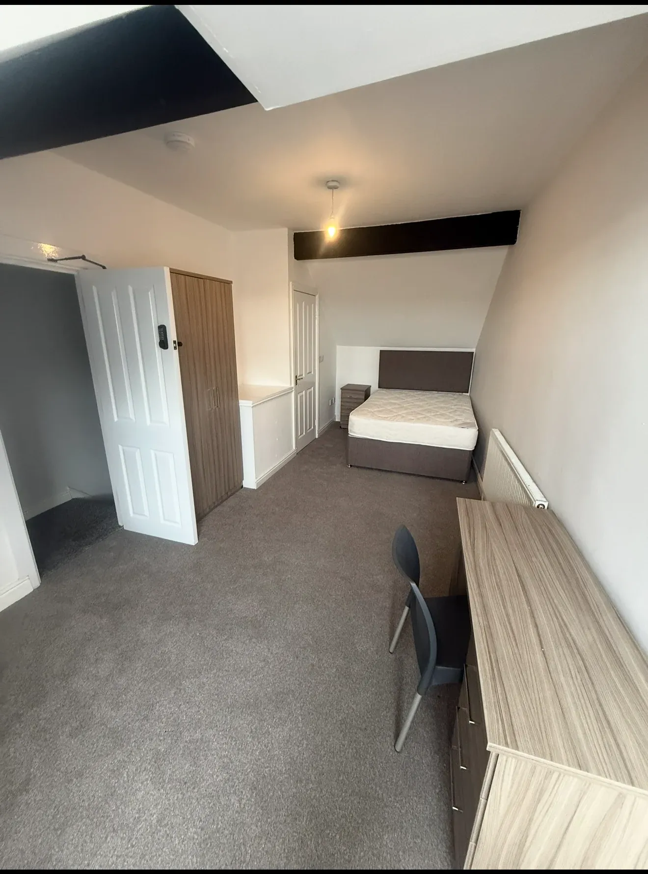 A finished bedroom at King Street, with a double bed, a long fitted desk and a sloping ceiling