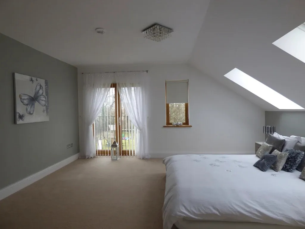 A finished loft conversion bedroom with a sloped ceiling and rooflights