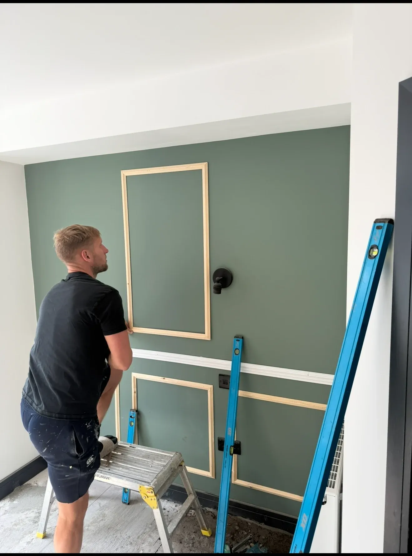 A joiner setting out panelling battens against a level before plastering