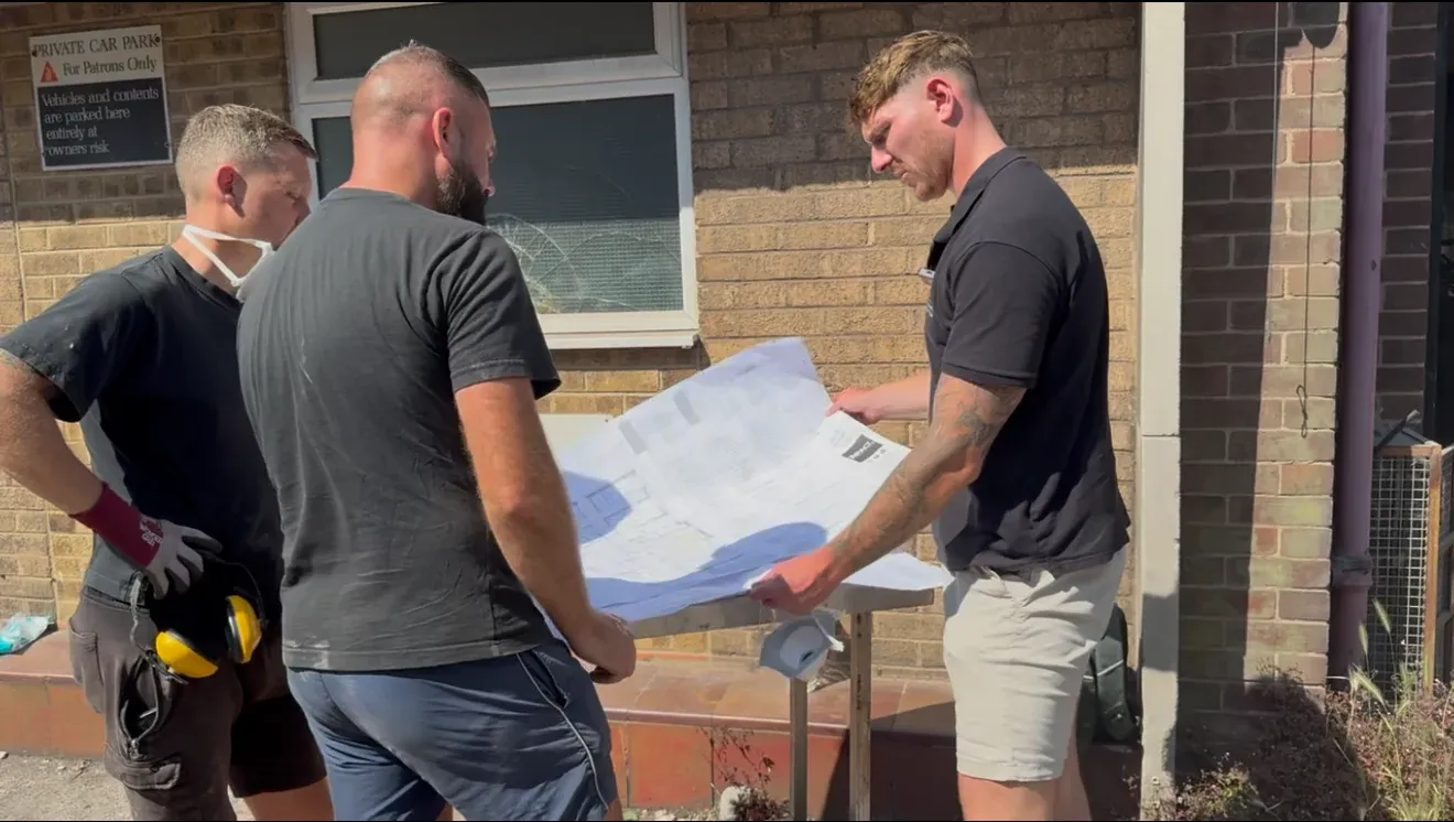 Three of the Stone & Barrow team on site, going through drawings on a workbench