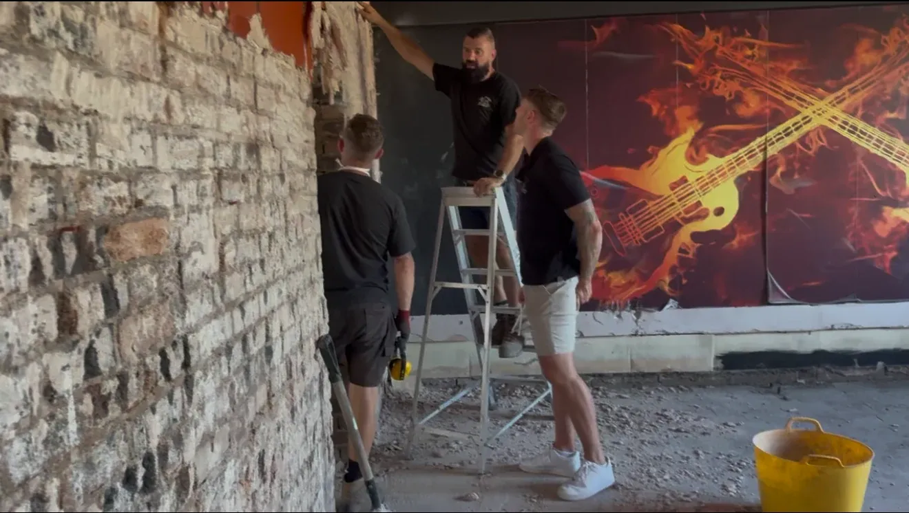 Two of the team working on an internal wall with a ladder and exposed brickwork