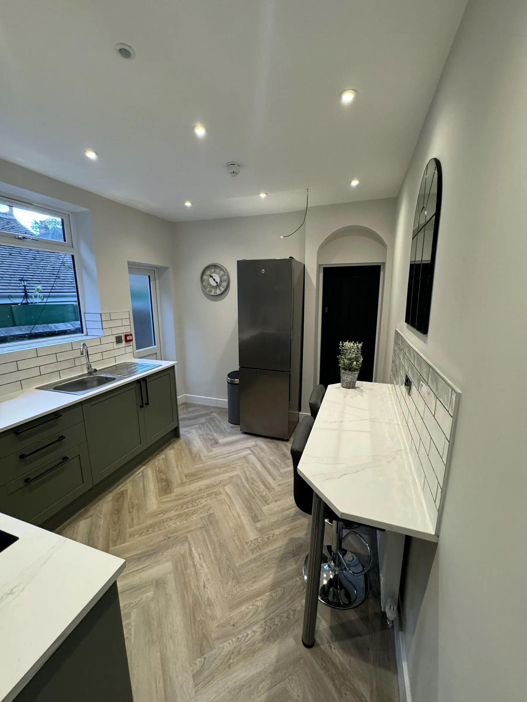 The kitchen from the far end, with a window over the sink and an American fridge freezer