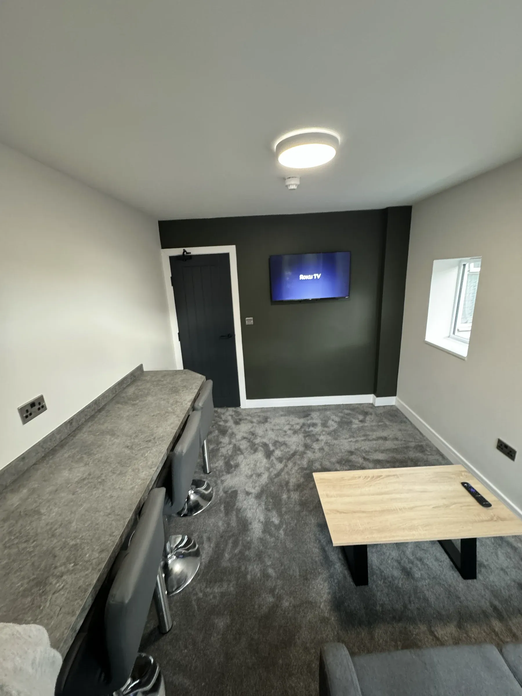 The communal living space with a wall-mounted television, dark feature wall and a low table