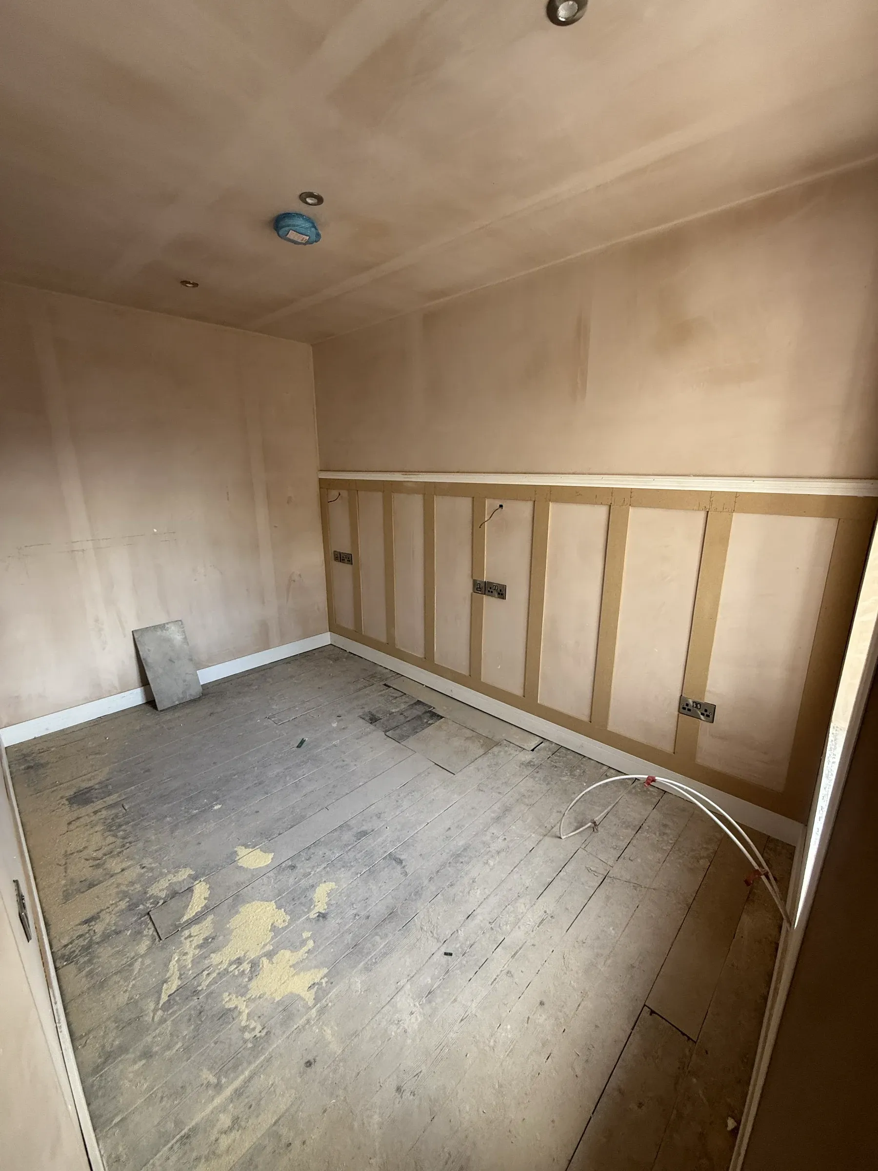 The same bedroom at first fix, with new stud partitions and panelling battens fixed to bare walls