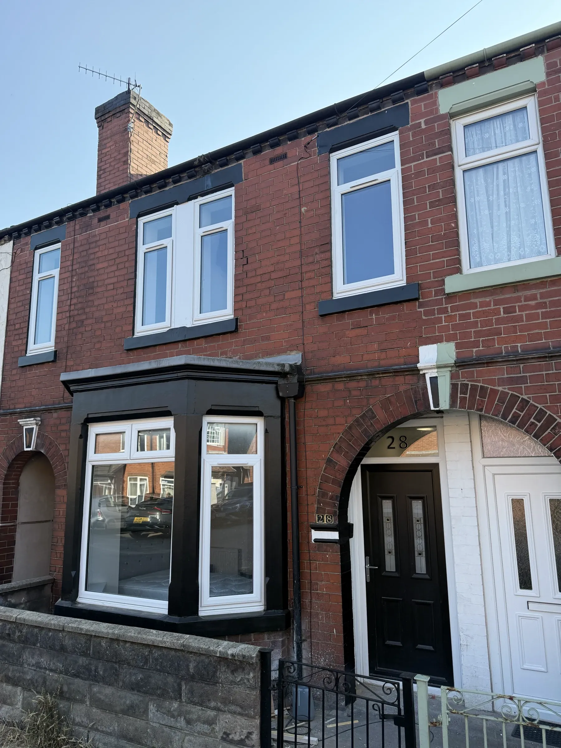 The front elevation of Oxford Road, a bay-fronted red brick terrace with new black windows and door