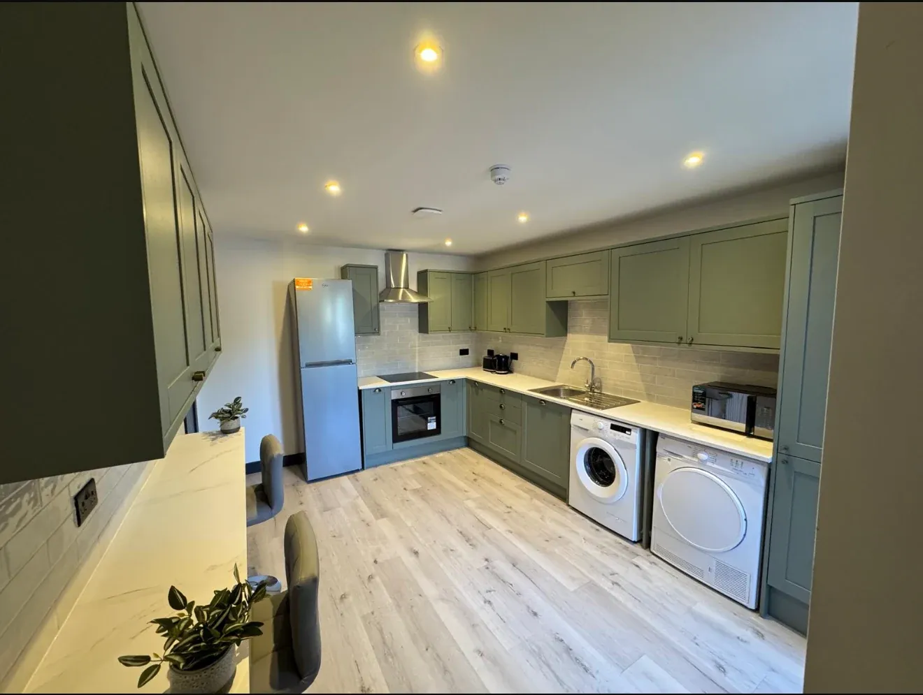 The finished communal kitchen at Oxford Road, with sage green shaker units, stone worktops and integrated appliances