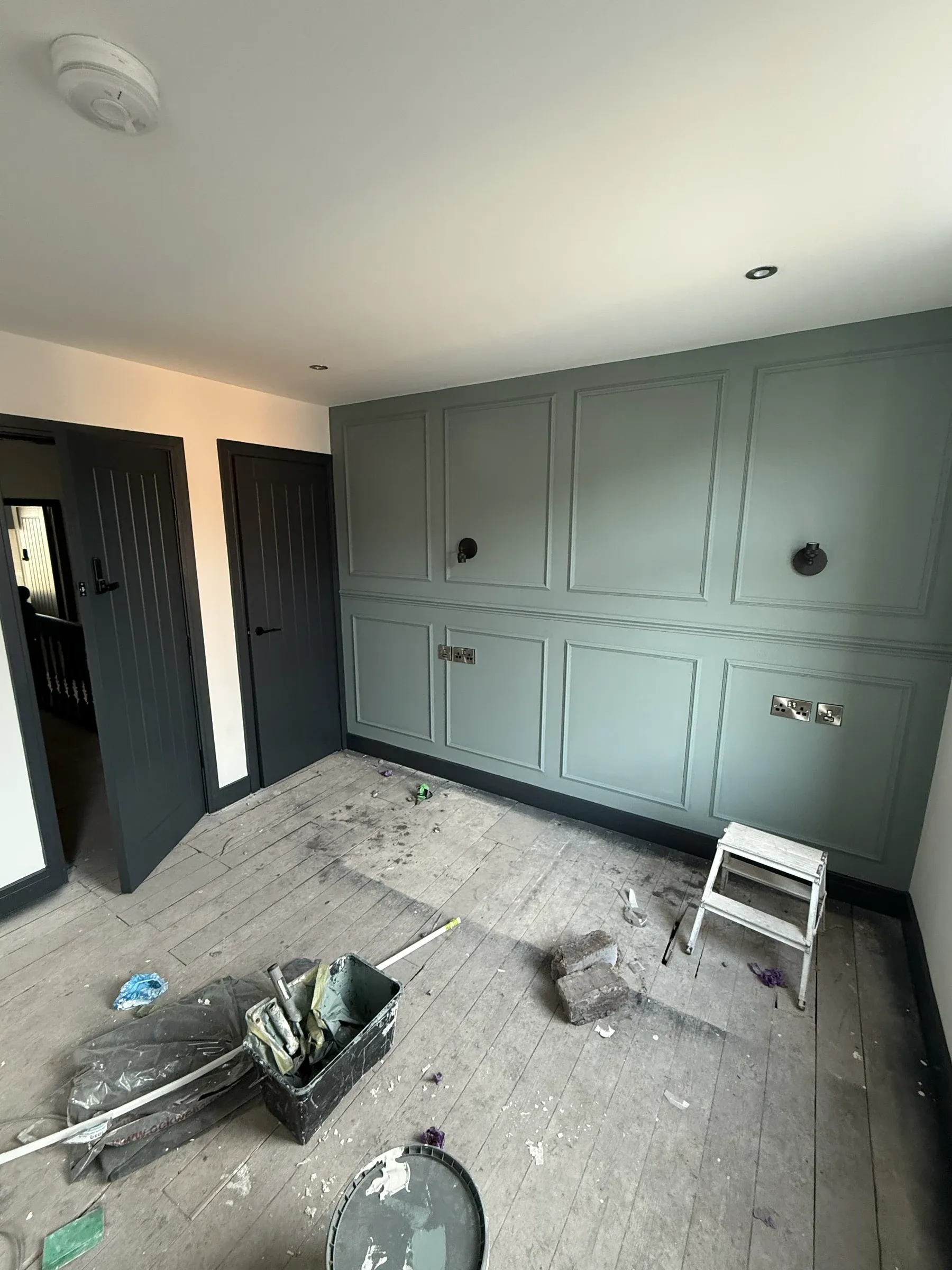 A finished room at Oxford Street with fitted sage green wardrobes and dark painted doors