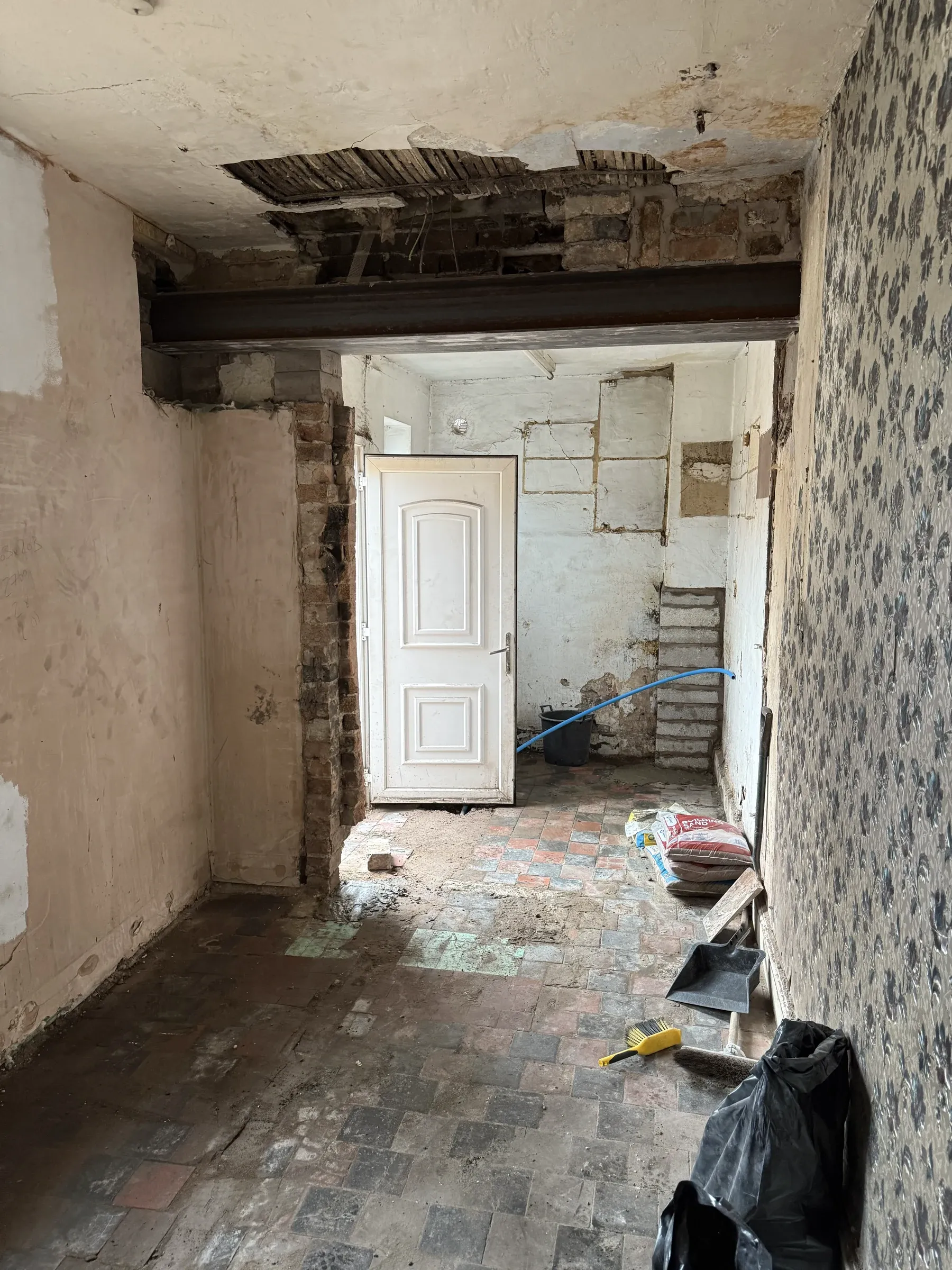 A room stripped back with the ceiling down to the joists and the original tiled floor exposed
