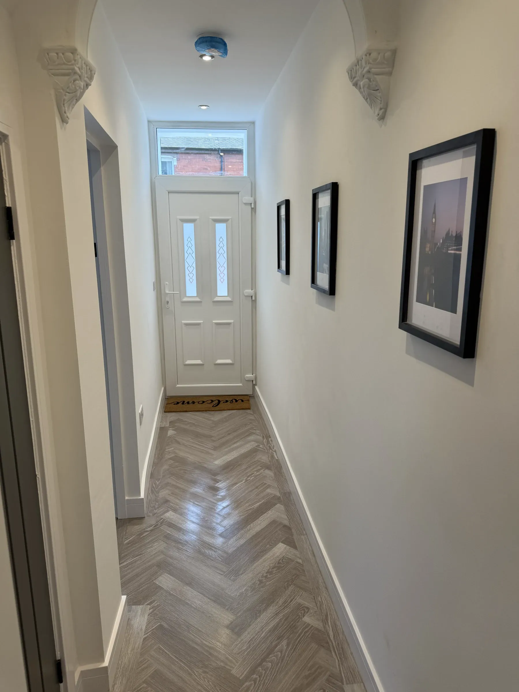 The finished hallway, with herringbone flooring, fresh white walls and the original front door restored