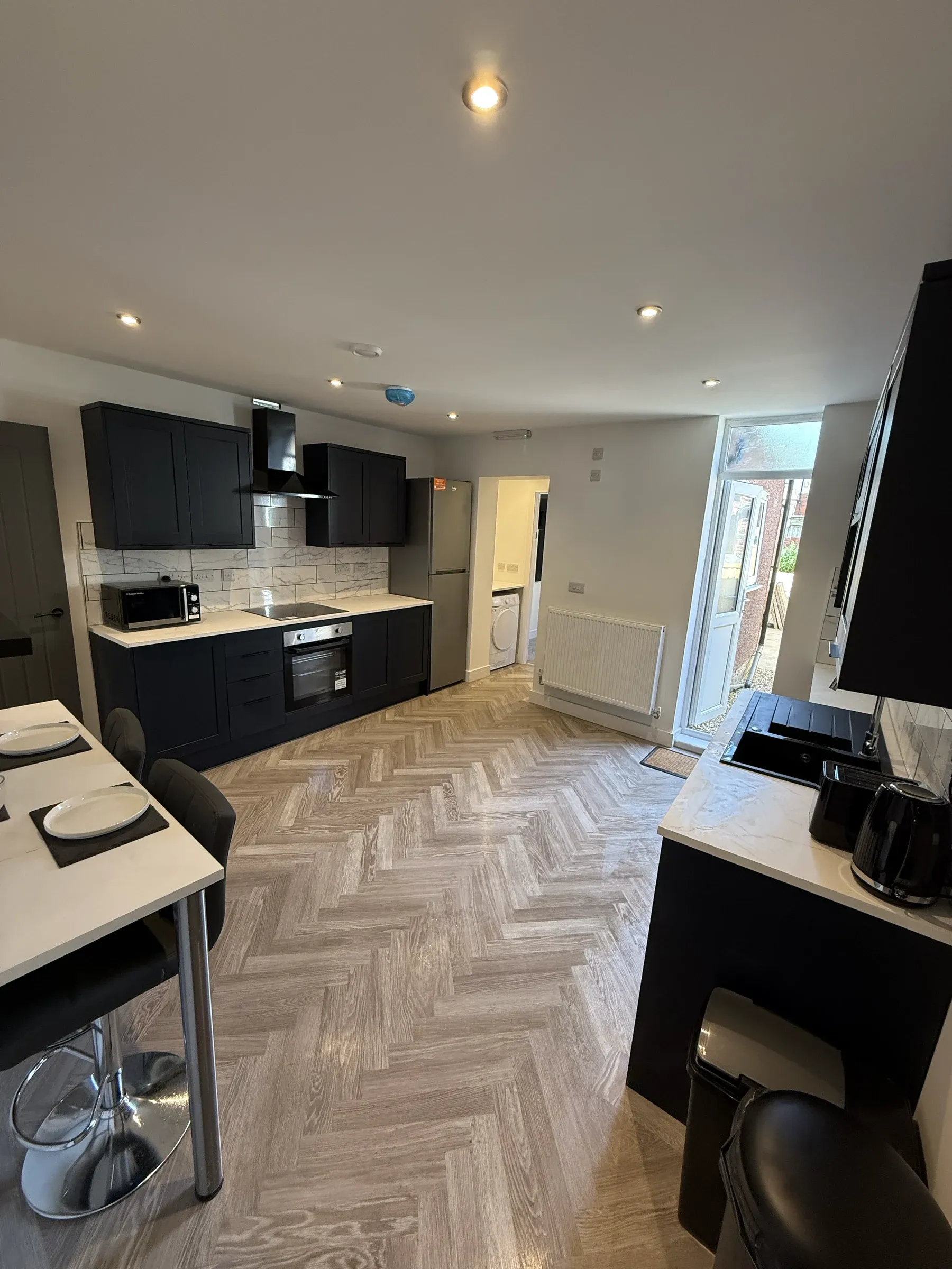 A finished kitchen with dark units, a breakfast bar and herringbone flooring