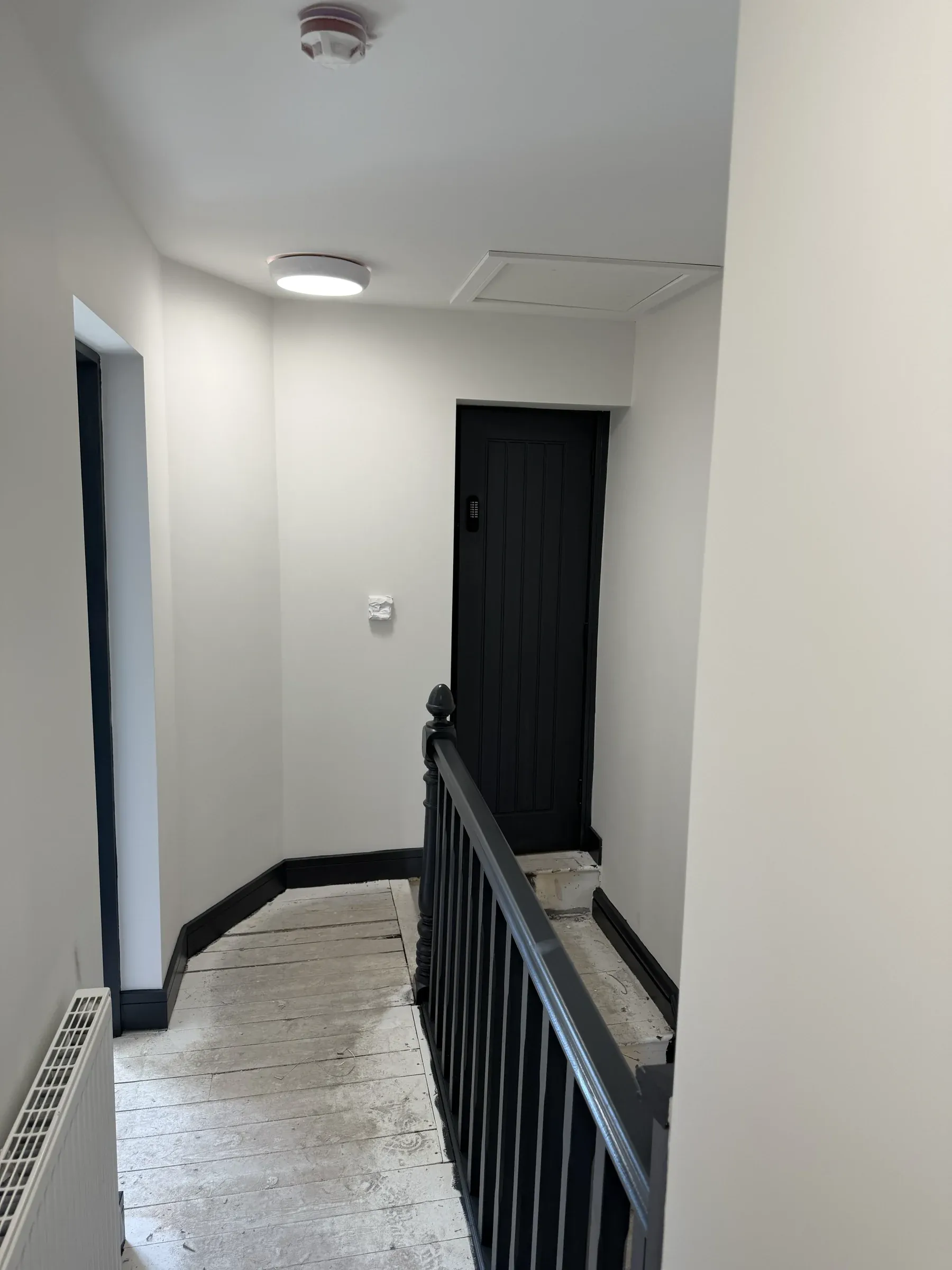 The finished first floor landing, with a dark bedroom door and new flooring