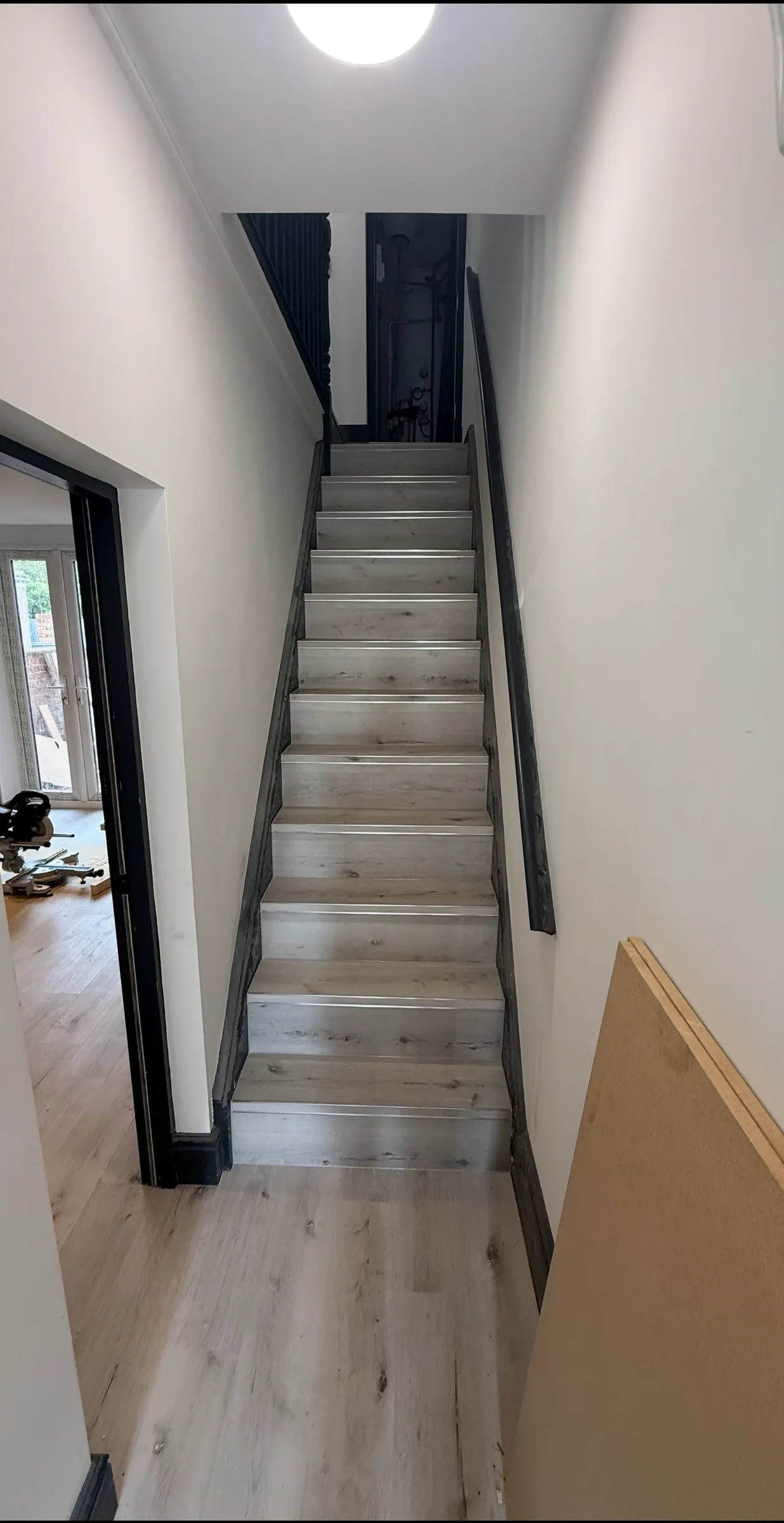 The finished staircase, painted white with new treads and a dark handrail