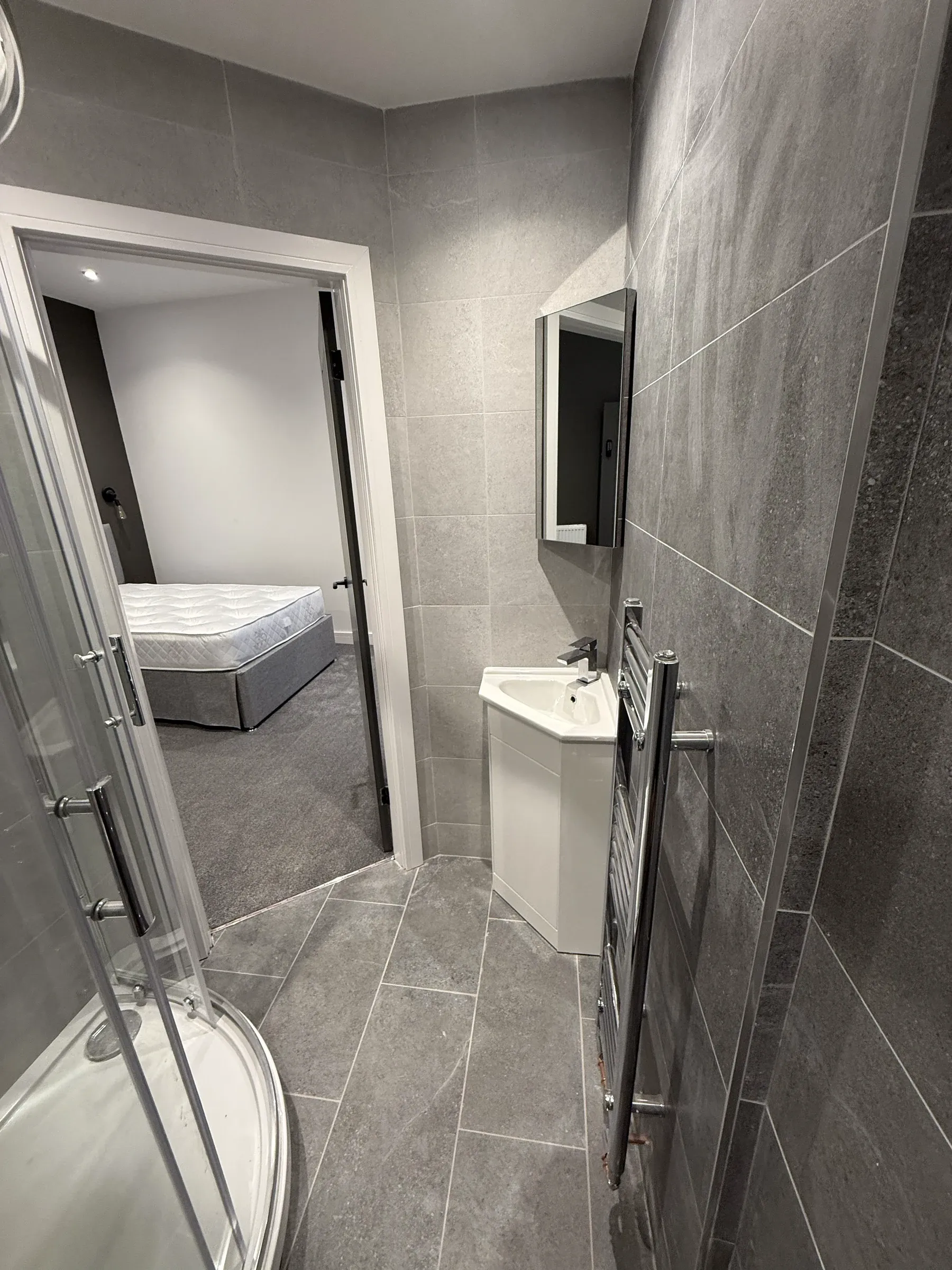 The en-suite looking through to the bedroom beyond, fully tiled in large format grey tiles