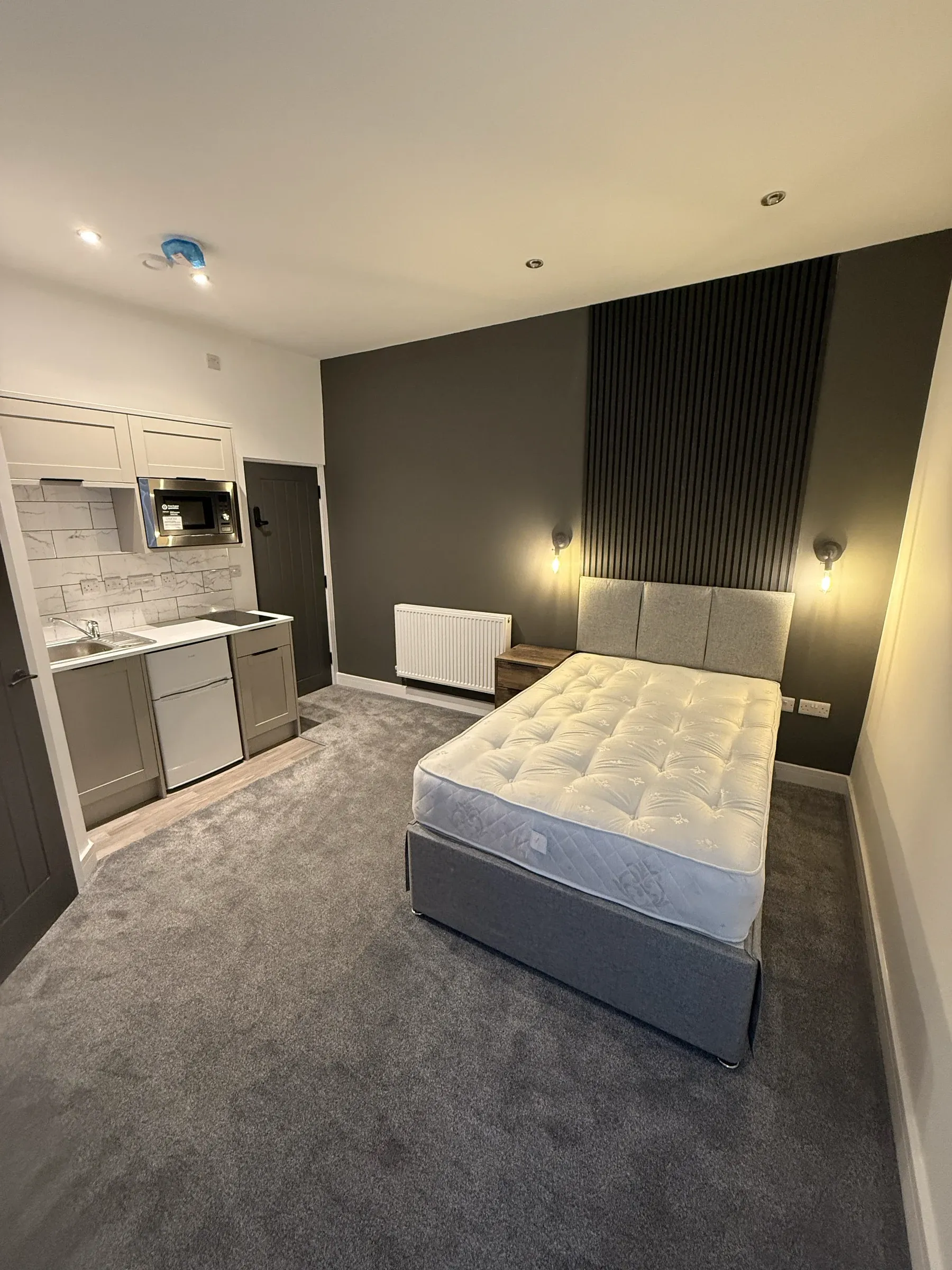 A finished en-suite letting room with a fitted kitchenette, slatted feature wall and double bed