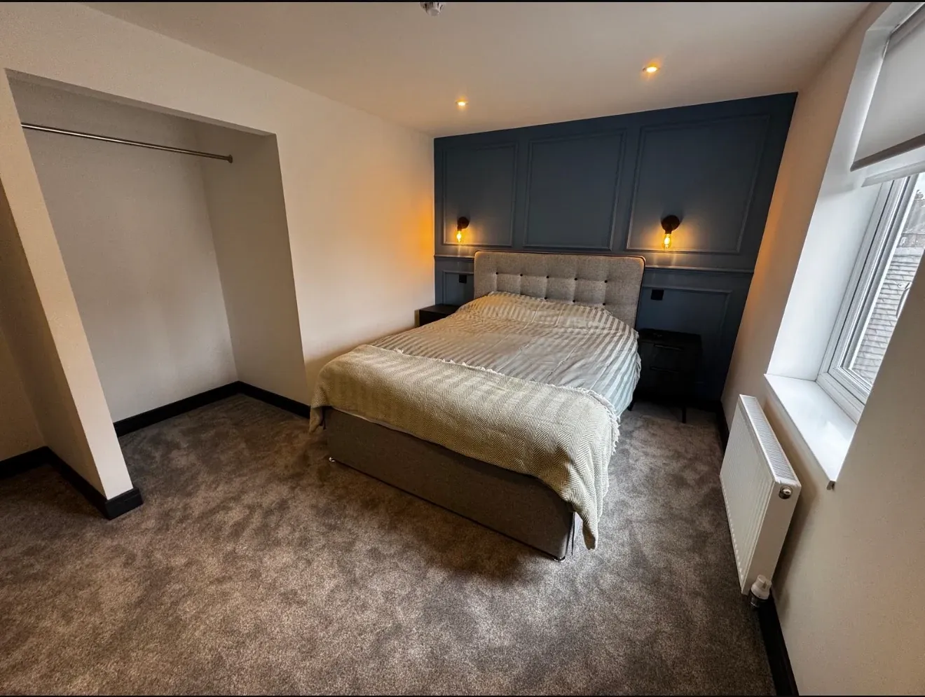 A second finished bedroom with a navy alcove, buttoned headboard, fitted wardrobe and window seat