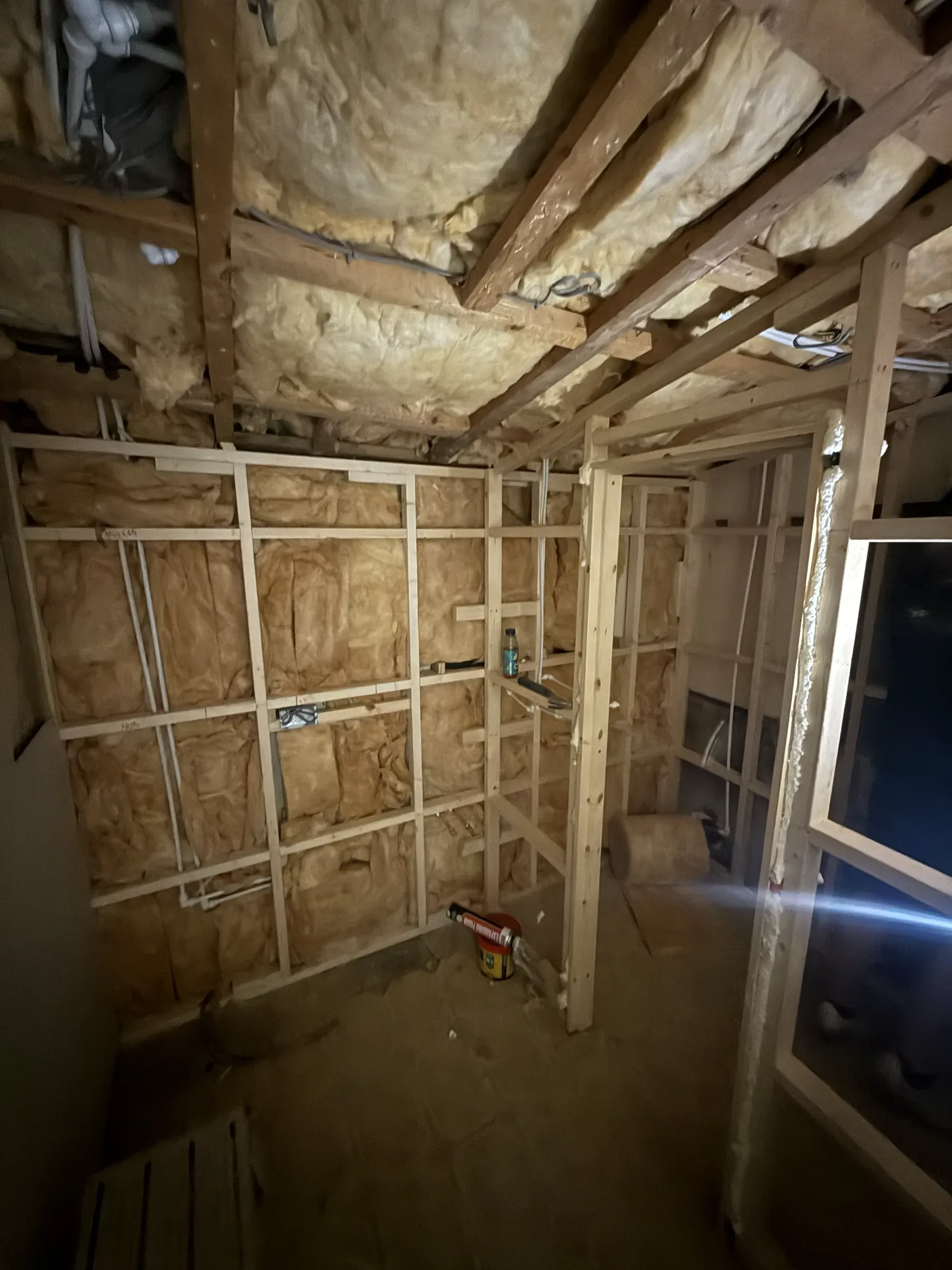 A room at first fix, with new timber stud partitions, insulation between the joists and bare boards