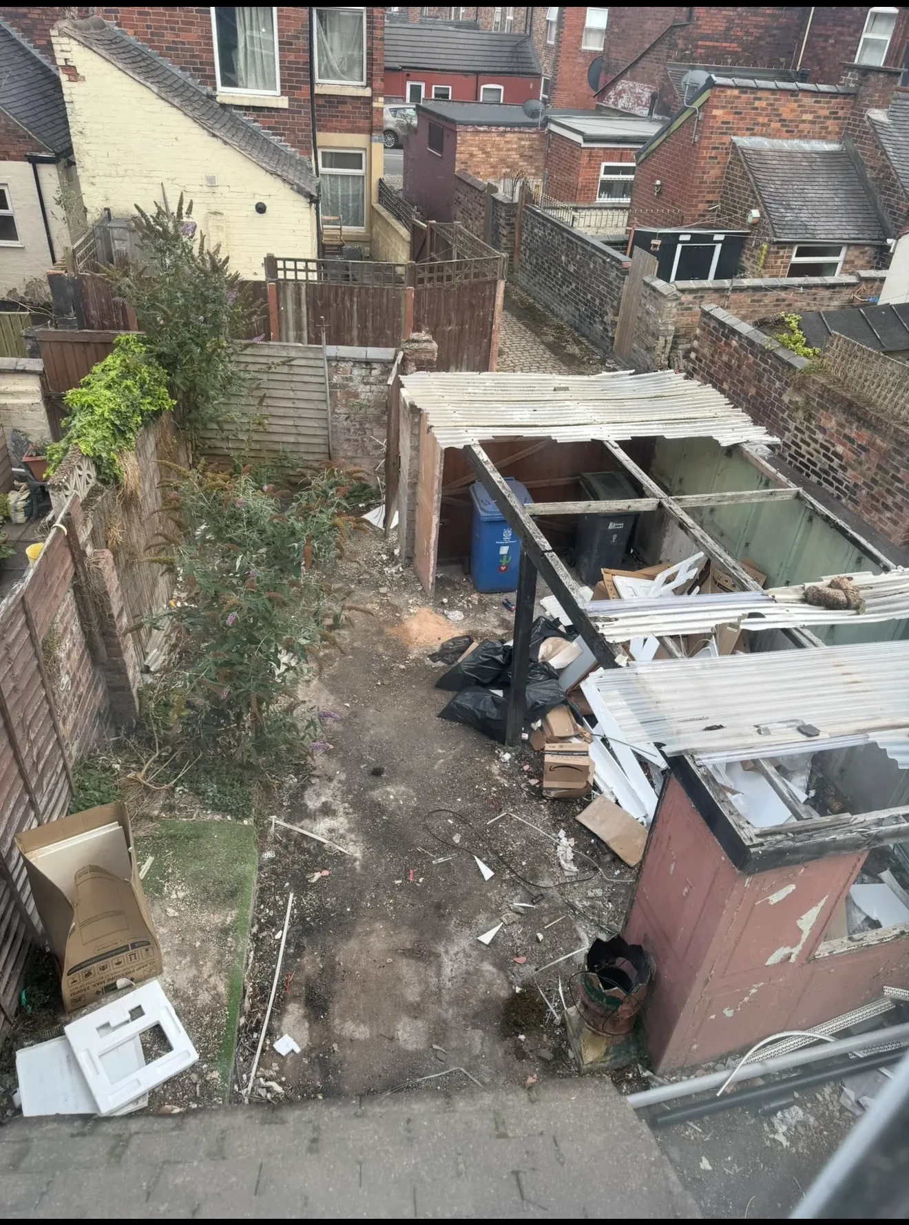 The rear yard before work, with a collapsed lean-to, rubbish and overgrown ground