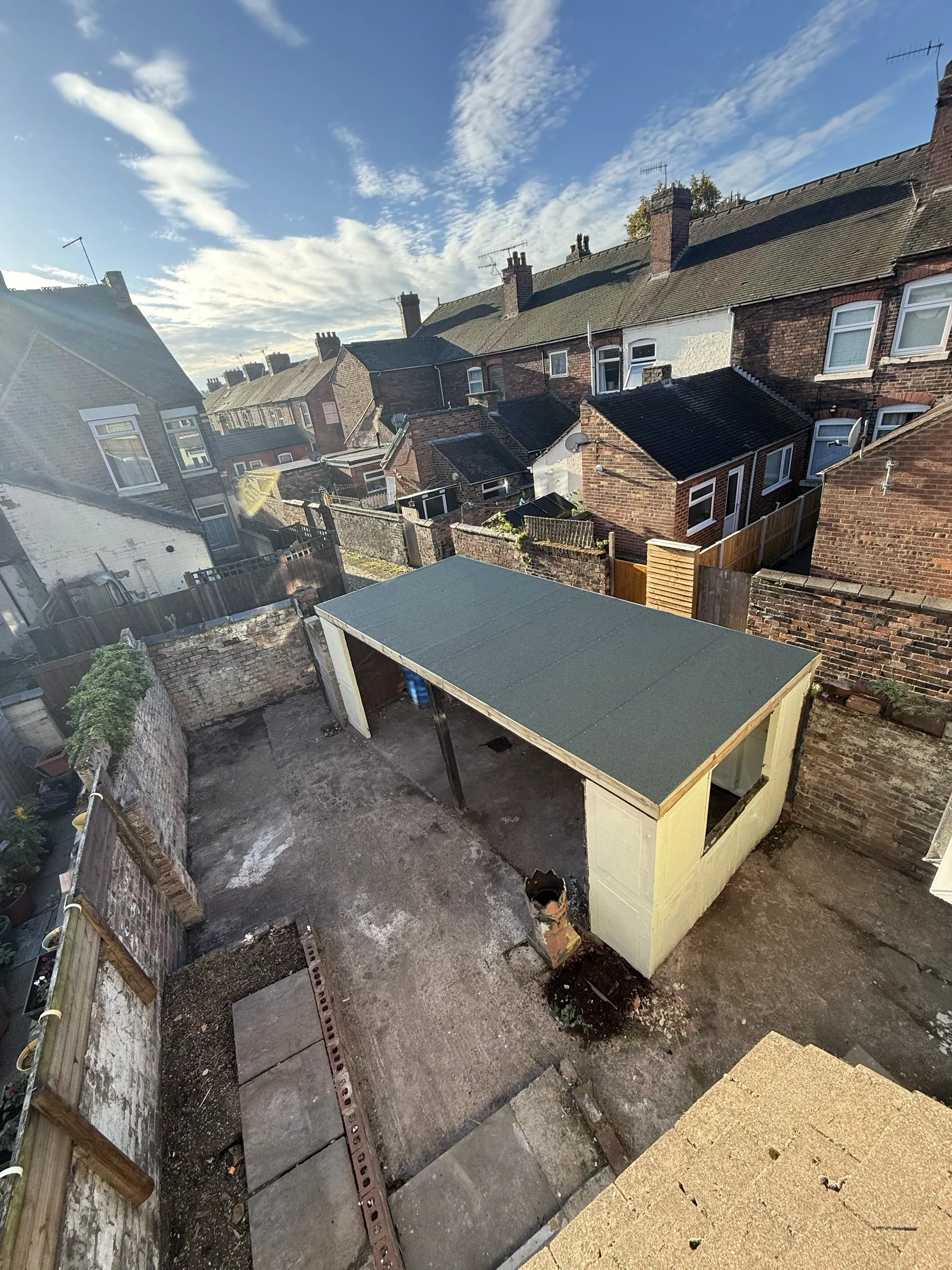 The rear yard cleared and rebuilt, with a new flat-roofed outbuilding and level paving